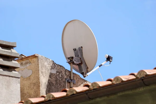 青空を背景に民家の壁面に設置された衛星アンテナ — ストック写真