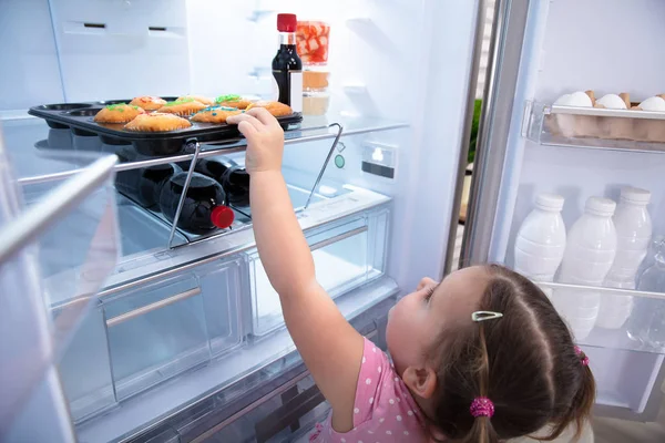 Cute Little Girl Trying Reach Out Pick Cupcakes Fridge Home — Stock Photo, Image