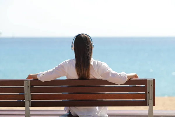 Vista Trasera Una Mujer Escuchando Música Contemplando Océano Sentada Banco — Foto de Stock