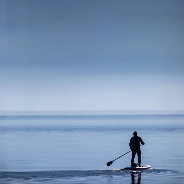 一个男人站在湖上的一块木板上 — 图库照片