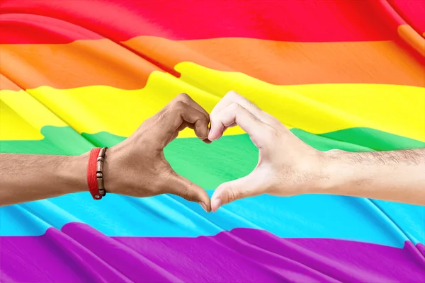 虹のフラグの背景を持つ手でハートサインを作るゲイのカップル Lgbt コンセプト — ストック写真