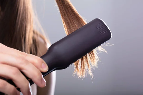 Close Mulher Alisamento Cabelo Com Alisador Contra Fundo Cinza — Fotografia de Stock