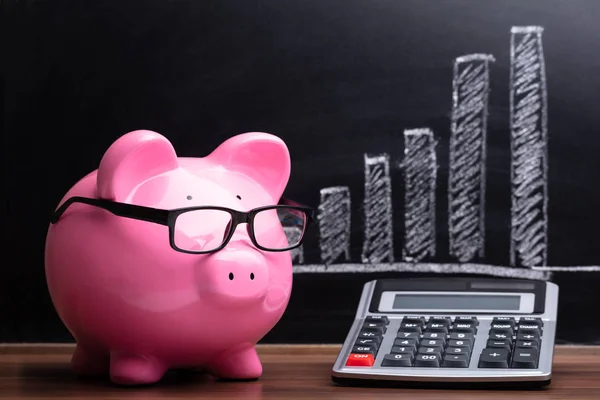 Close Pink Piggybank Calculator Front Blackboard Showing Graph — Stock Photo, Image