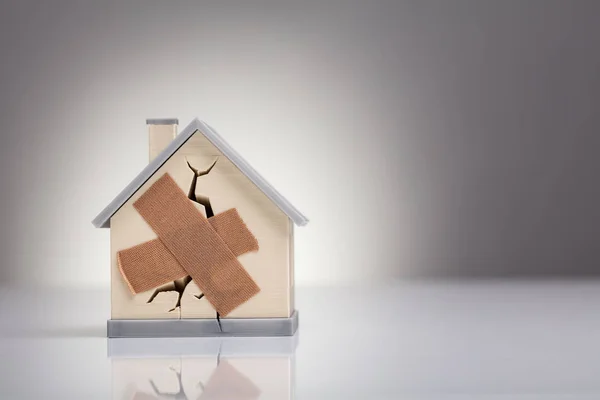 Broken House Model Met Gekruiste Pleister Het Bureau — Stockfoto