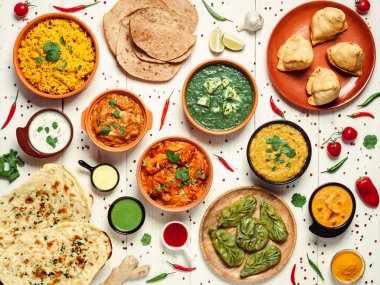 Indian cuisine dishes: tikka masala, dal, paneer, samosa, chapati, chutney, spices. Indian food on white wooden background. Assortment indian meal top view or flat lay. clipart