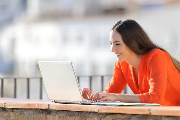 在阳台上的笔记本电脑上写橙色工作的快乐创业者 — 图库照片