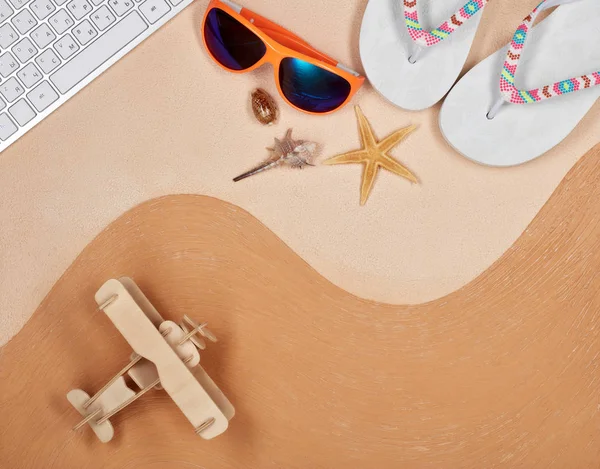 Flip flops, sunglasses, seashells, model of plane and computer keyboard  lying on textural double background consisting of two beige shades. Top view with copy space, Travel agency. Internet shop