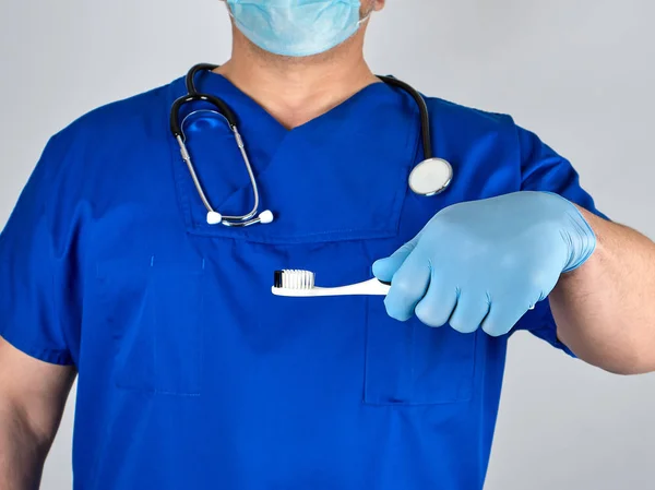 医生在无菌乳胶手套和蓝色制服拿着牙刷 口腔卫生概念 — 图库照片