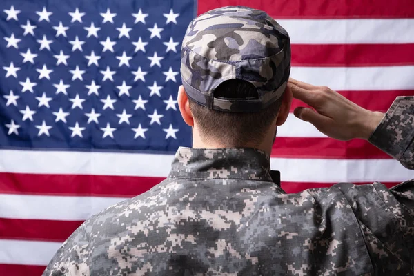 私たちの旗を敬礼する軍人の背面図 — ストック写真