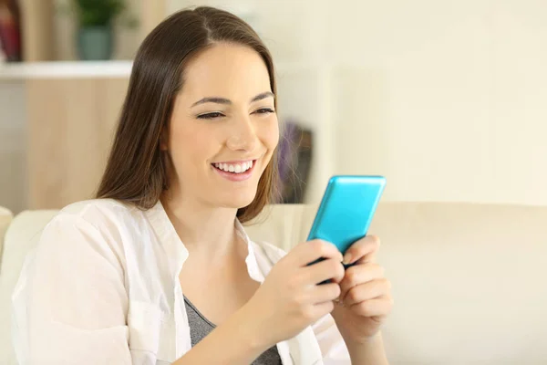 Mujer Sonriente Usando Teléfono Inteligente Azul Sentado Sofá Sala Estar — Foto de Stock
