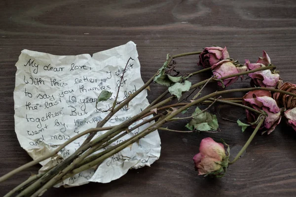 Stary Pogruchotany List Pożegnalny Uschniętymi Różami Brązowym Drewnianym Stole Jako — Zdjęcie stockowe