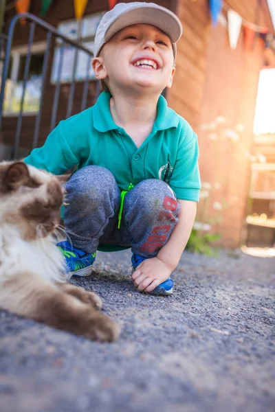 농장에서 고양이 모피를 쓰다듬는 행복한 소년의 초상화 — 스톡 사진