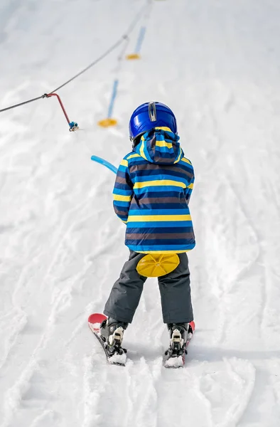 小男孩滑雪者被一个小小的圆形手持滑雪车拖着上山 — 图库照片