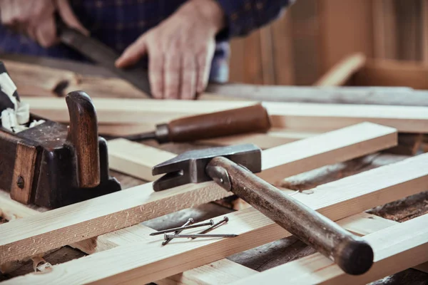 木匠在车间里工作 用的是新铺好的木板 前面是旧的手工工具和钉子 — 图库照片