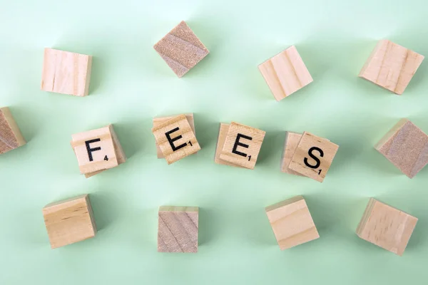 Concept Fees: Wooden cubes with the letters Fees on green background