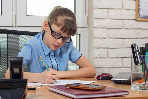 オフィスのテーブルで８歳の少女が紙に噴水のペンを書いている — ストック写真