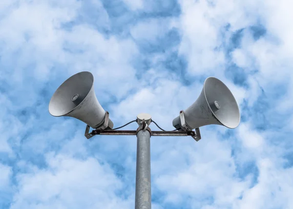 Old loud speakers isolated on the blue sky background with white clouds.