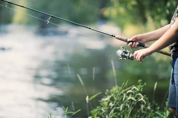 钓鱼竿和卷轴在河上的手 — 图库照片