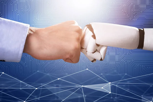 Robot And Human Hand Making Fist Bump On Blue Digital Backdrop