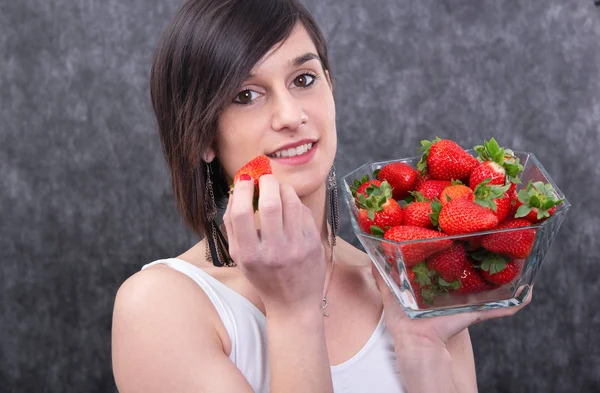 微笑漂亮的年轻黑发女人吃草莓 — 图库照片