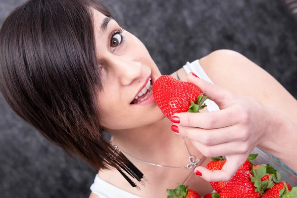微笑漂亮的年轻黑发女人吃草莓 — 图库照片