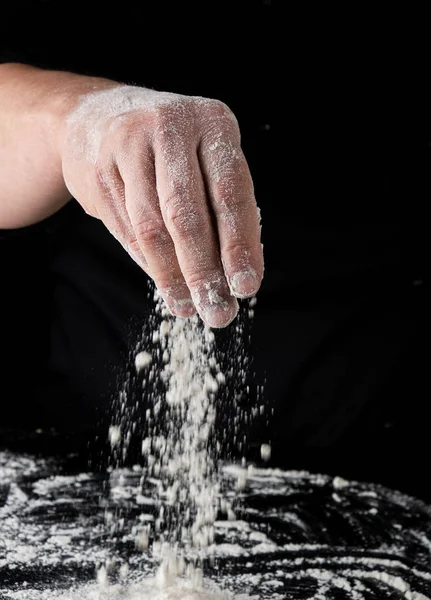 Svart Uniform Sållar Genom Fingrarna Vitt Vetemjöl Över Bordet Svart — Stockfoto