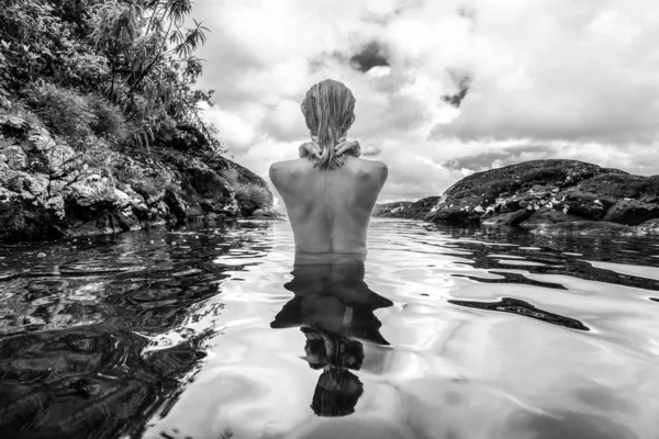 入浴や熱帯モーリシャス島の自然公園に 500 フィートの滝の前に自然のスイミング プールでリラックスした美しい裸の女性の後姿 黒と白のイメージ — ストック写真