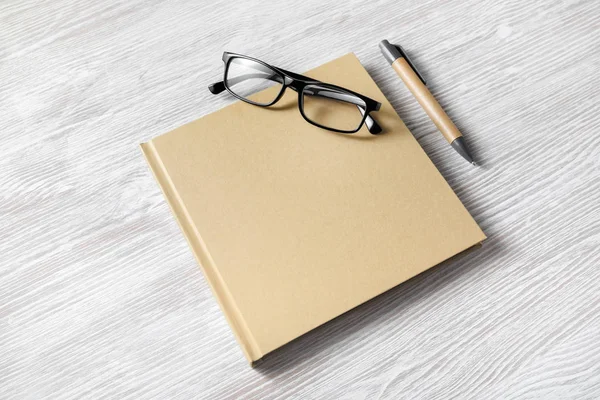 Foto Eines Geschlossenen Quadratischen Buches Brille Und Stift Auf Hellem — Stockfoto