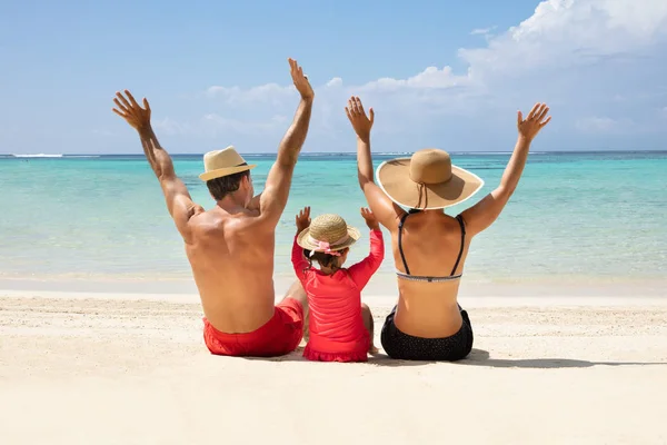 Vista Trasera Familia Sentada Arena Levantando Sus Manos Disfrutando Playa — Foto de Stock