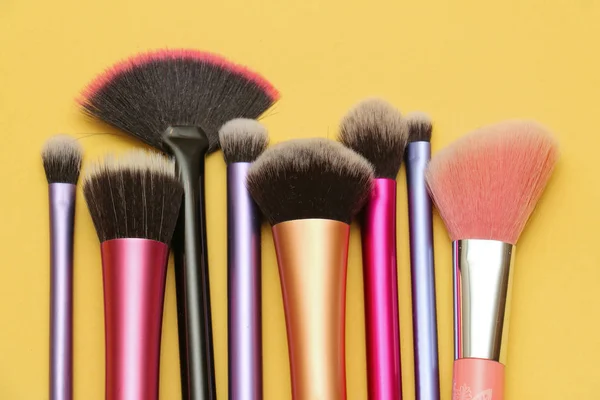 Colorful face make up brushes for face and eyes on yellow background