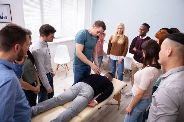 Male Instructor Teaching Massage Technique To Group Of Multi-ethnic People