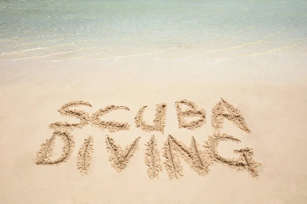 Close-up Of Scuba Diving Text Written On Sandy Beach Near The Seashore