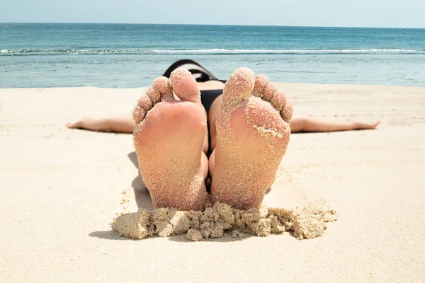 特写镜头的一个年轻女子躺在沙滩上与她凌乱的脚 — 图库照片