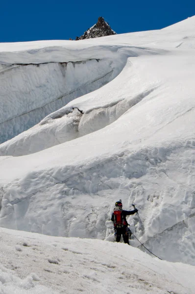 黒い服を着た男性登山家が雪の斜面を登る 冬空の日 — ストック写真