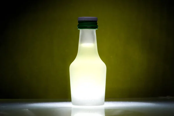 Mała Butelka Likieru Cytrynowego Żółty Blask Tle Biały Poślizg Podłodze — Zdjęcie stockowe