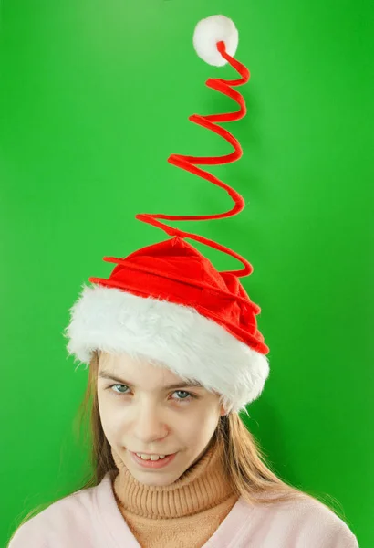 かわいいサンタの女の子 緑の背景にクリスマス帽子をかぶった十代の少女のクローズアップ肖像画 — ストック写真