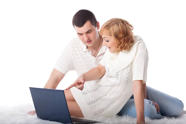 一对带着笔记本的快乐的年轻夫妇坐在白色的背景上 — 图库照片