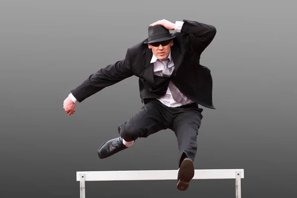 businessman jumps over hurdle