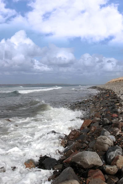 一个卵石海滩在明亮的一天与平静的海浪溅在鹅卵石作为背景 — 图库照片