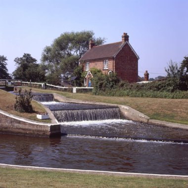 Lock and weir with old lock keepers cottage on the River Wey at Ripley in Surrey. England clipart