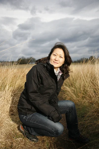 亚洲女人面带微笑地看着田野里的相机 — 图库照片