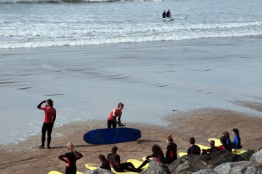 surfing school students being taught on the beach in lahinch county clare ireland on a beautiful day clipart