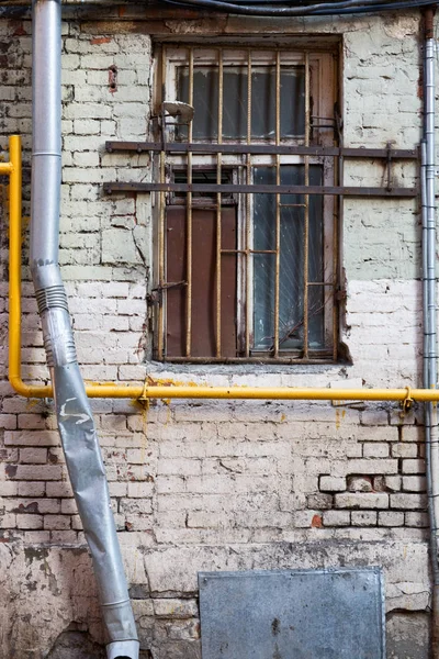 レンガの壁に格子窓 ケーブル 水道管 — ストック写真