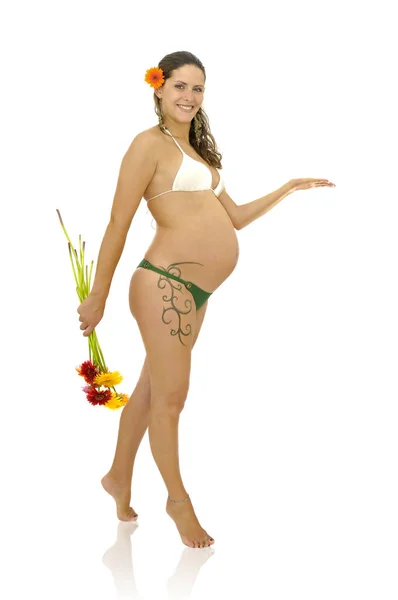 在比基尼身上有纹身的孕妇拿着一束白色的花 — 图库照片