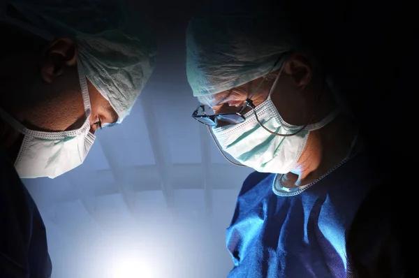 黑暗背景下的外科医生团队 — 图库照片