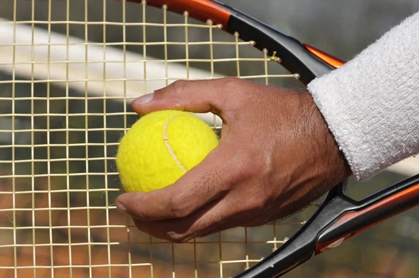 Player's hand with tennis ball preparing to serve