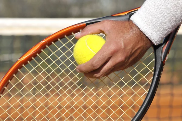 Player's hand with tennis ball preparing to serve