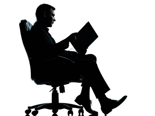 古代の本のシルエットを読んでアームチェアに座っている1人の白人ビジネスマン白の背景に隔離されたスタジオでの完全な長さ — ストック写真