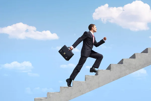 Image of confident businessman with briefcase walking upstairs