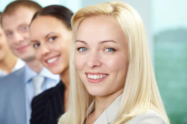 Businesspeople standing in a row, the focus is on blond woman